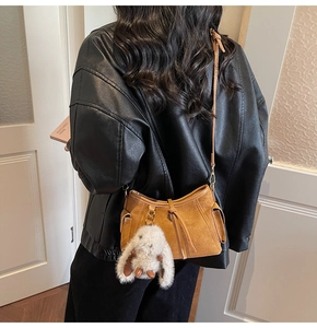Detail of tan suede crossbody bag with fringe drawstring and cute white rabbit charm