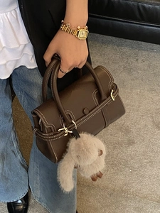 Brown leather bowling bag with white contrast stitching and plush rabbit pendant