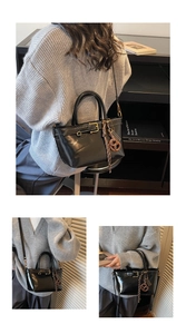 Macro view of vintage black glossy leather Boston bag with a cute biscuit charm