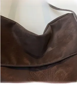 Detailed macro view of dark brown faux leather tote with embossed sunflower pattern