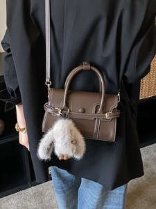 Chic brown leather bowling bag with contrast stitching and plush rabbit charm detail