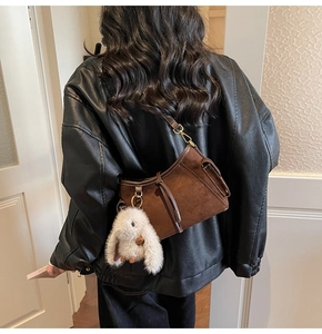 Detail of dark brown suede shoulder bag with drawstring and white rabbit plush charm