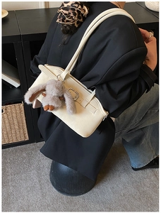 Détail du sac sous le bras crème en cuir grainé avec un pendentif lapin en peluche