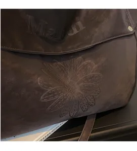Detail of embossed floral patterns and brand logo on premium leather tote bag