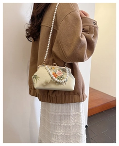 Detailed close-up of a vintage floral embroidery bag with pearl chain and metal clasp