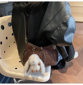 Detail of dark brown suede underarm bag with a soft grey fluffy rabbit charm