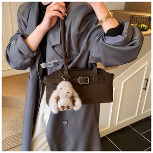 Détail d'un sac à main en cuir marron foncé avec boucle argentée et breloque lapin