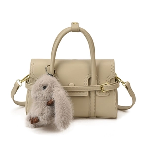 Chic beige structured leather crossbody bag with top handles and cute rabbit charm