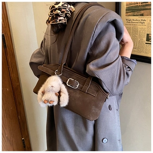 Gros plan du sac à main rétro marron foncé avec boucle argentée et charme de lapin