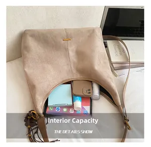Vue détaillée du grand sac cabas en daim beige montrant la capacité interne et l'élément doré