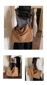 Detail view of large brown leather tote bag with leaf pattern texture and strap