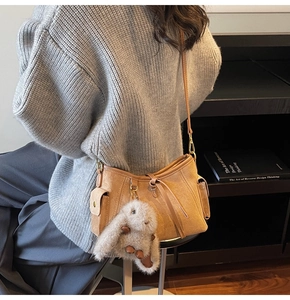 Detail of suede crossbody bag with functional side pockets and a cute rabbit charm