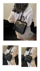 Detail view of the black textured leather backpack with top handle and front zipper pocket