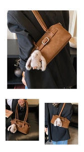 Sac Boston rétro marron avec pendentif lapin, porté à l'épaule et à la main