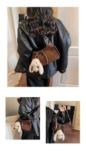 Detail view of brown suede baguette bag featuring a plush rabbit charm and leather strap