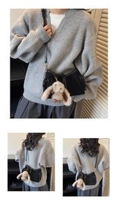 Detail of black leather shoulder bag featuring white stitching and a plush rabbit pendant