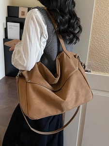 Sac bandoulière en suédine marron avec motif floral en relief porté par un mannequin
