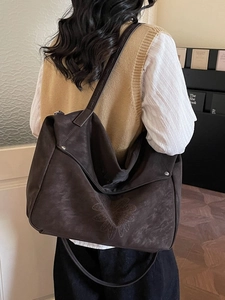 Grand sac cabas marron en daim avec gaufrage floral porté par un mannequin femme