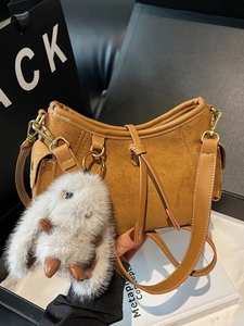 Brown suede shoulder bag with long strap and a large white plush bunny charm