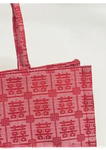 Detail of red Chinese wedding tote bag featuring woven Xi character texture and stitching