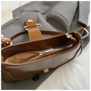 Detailed interior of vintage brown leather underarm bag with zipper pocket and adjustable strap