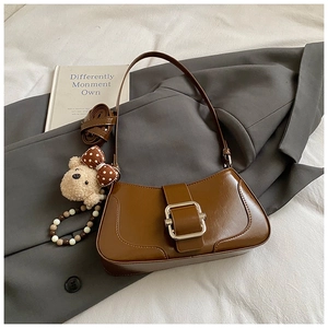 Detail of caramel PU leather bag with decorative silver buckle and plush bear pendant