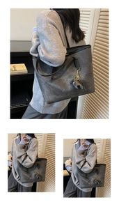 Detail of grey large capacity tote bag with elephant charm and textured leather finish