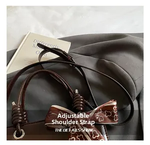 Detail of adjustable metal buckle strap on vintage dark brown glossy leather handbag