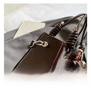 Detail of vintage brown patent leather handbag with beaded handle and silk scarf decor