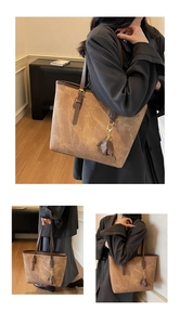 Close-up of brown textured tote bag with dark handles and a small elephant charm