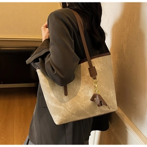 Detail of grey marble tote bag with brown leather handles and elephant charm on model