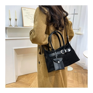 Detail of black suede tote bag with metal buckle and mini pouch worn over a camel coat