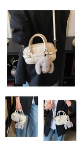 Creamy white Boston handbag with grey bunny charm shown in handheld and crossbody styles