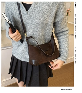 Detail of dark brown suede and leather crossbody bag with polished gold hardware