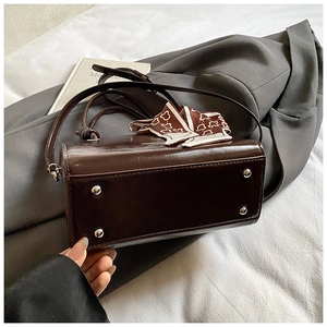 Detail of vintage brown square bucket bag with metal studs and decorative silk scarf