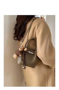 Detail of lychee pattern leather bucket bag with silver lock and plush bear charm