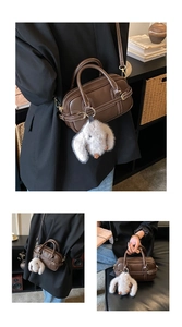 Detail showing vintage dark brown leather bag with white stitching and plush rabbit charm