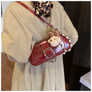 Close-up of wine red glossy handbag with silver buckle and decorative bear charm