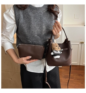 Detailed shot of dark brown pebbled leather bucket bag with a cute bear charm accessory
