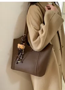 Détail d'un sac cabas marron café avec charme de chat en peluche et texture similicuir