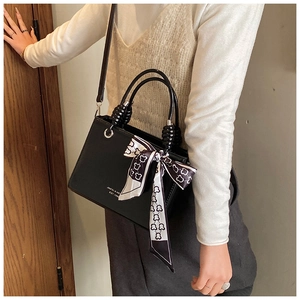 Detail of black rectangular crossbody bag with silk scarf and logo on textured leather
