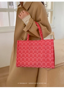 Detail of red wedding tote bag with Xi character patterns worn with a beige coat