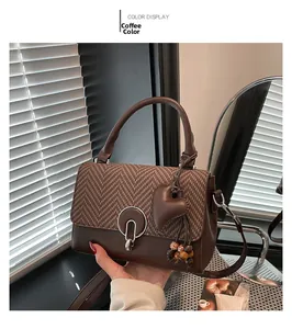 Detail of coffee brown crossbody bag with herringbone texture and heart charm