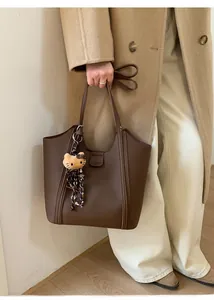 Vue détaillée du sac cabas en cuir marron foncé avec un pendentif peluche stylé