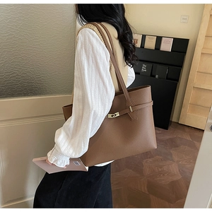 Detail of dark brown lychee leather tote bag with metal buckle shown in a lifestyle scene