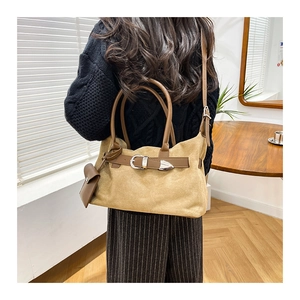 Detail of khaki suede tote bag featuring brown leather straps and a mini coin purse charm