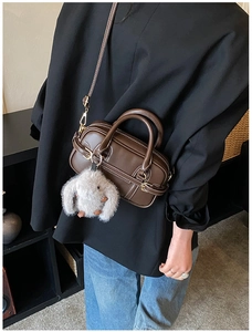 Detail of dark brown leather Boston bag with contrast stitching and rabbit charm