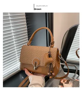 Detail of vintage brown houndstooth crossbody bag with metal ring lock and tassel charm