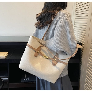 Detail view of large tote bag with cream leather texture and golden metal twist lock