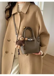 Taupe lychee grain leather bucket bag with silver lock and a cute bear bag charm
